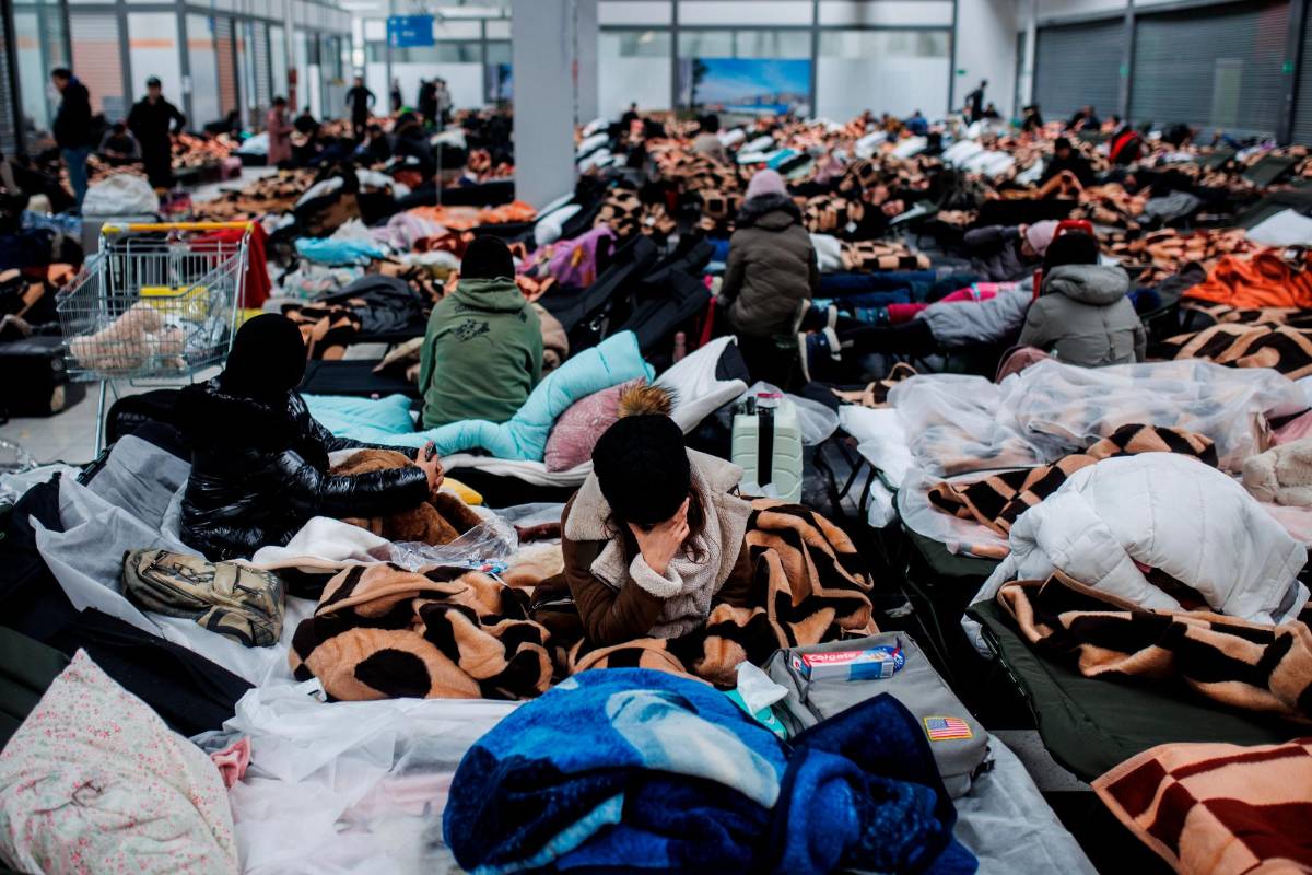 Centenares de personas descansan en un centro comercial destinado a la recepción temporal de refugiados que llegan a Polonia. Foto: Getty