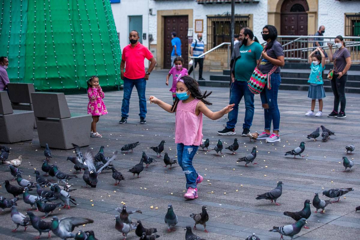 Niños jugando con las palomas en el parque principal de Envigado aprovechando con sus familias el fin del toque de queda. Foto: Carlos Velásquez