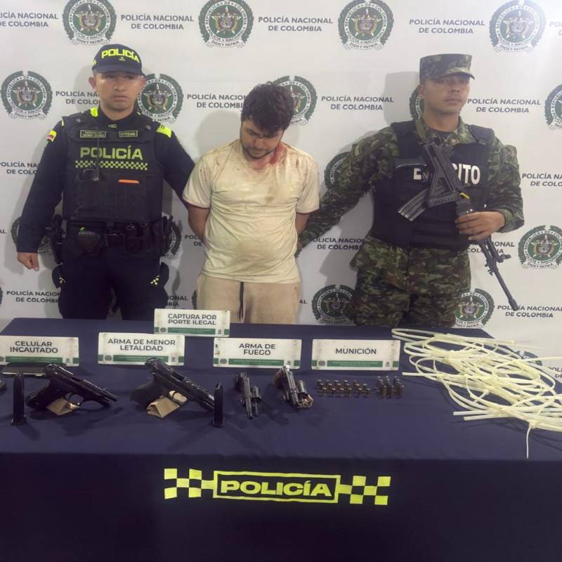 Adelante, parte de las armas encontradas por las autoridades. Atrás, uno de los detenidos. FOTO: Cortesía