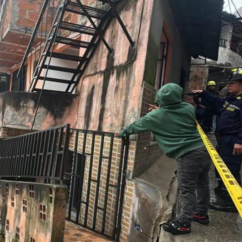 Adelante, una de las grietas que apareció en una de las viviendas afectadas. Atrás, el cierre de las edificaciones por parte de las autoridades. FOTO: Cortesía