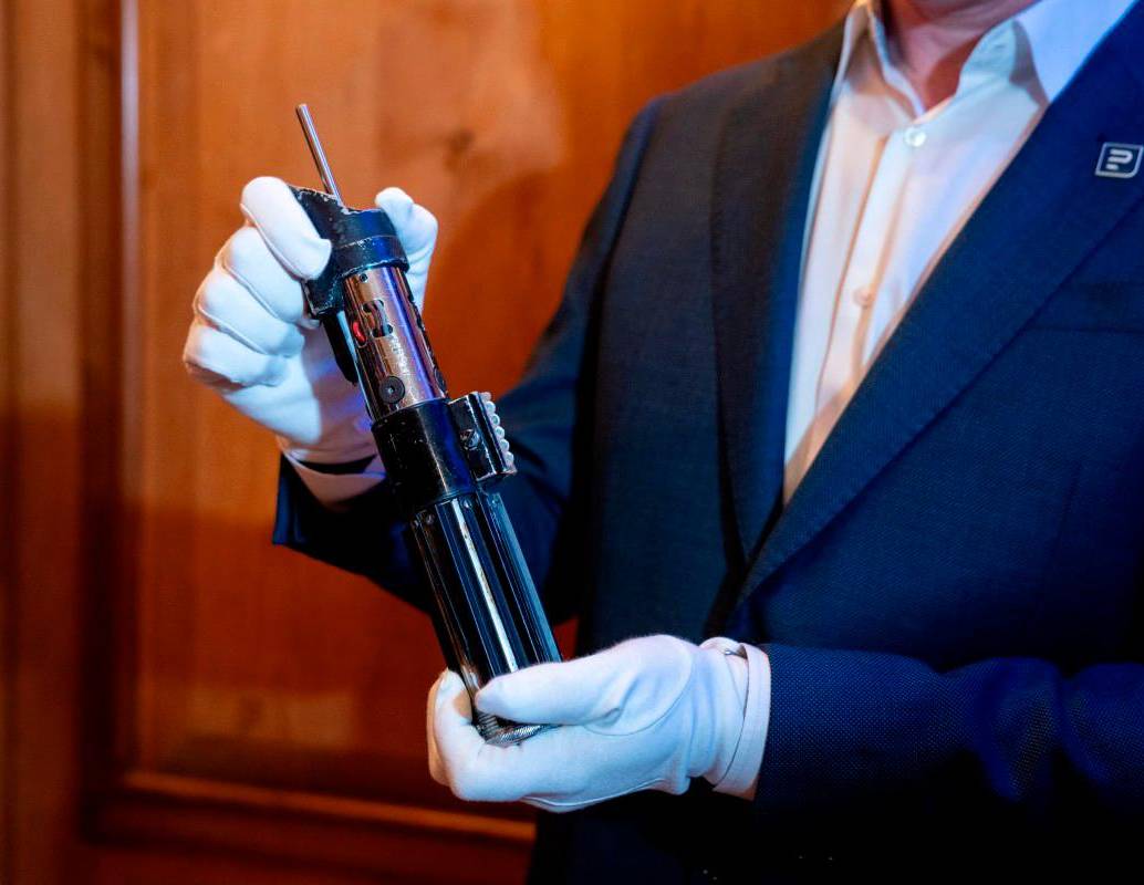 Un miembro del personal sostiene el sable de luz del personaje Darth Vader de las películas Star Wars: El Imperio Contraataca y El Retorno del Jedi. Foto AFP