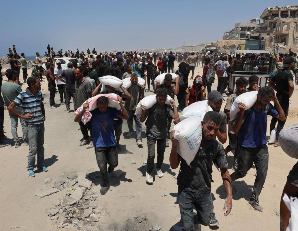 La gente camina por la calle al-Rashid, en el oeste de Jabalia, después de recibir ayuda humanitaria desde un punto de distribución de ayuda en el norte de la Franja de Gaza. FOTO: AFP