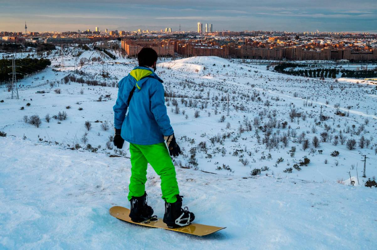 Un hombre haciendo snowboard en un barrio de Madrid con la vista del área de negocios de los rascacielos mientras la nieve ha caído en gran parte de España. Foto : Getty