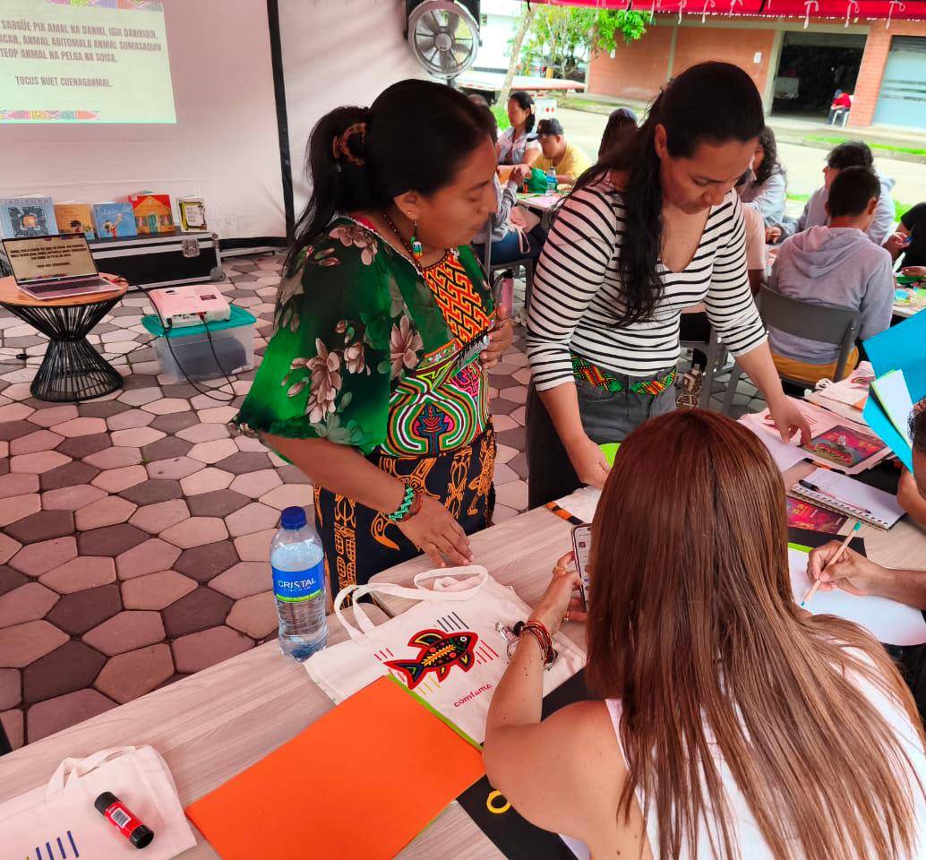 En compañía de Mileidy Cuéllar, indígena guna, Carmen Blanco revisa el trabajo de los asistentes al taller sobre molas. FOTO CORTESÍA