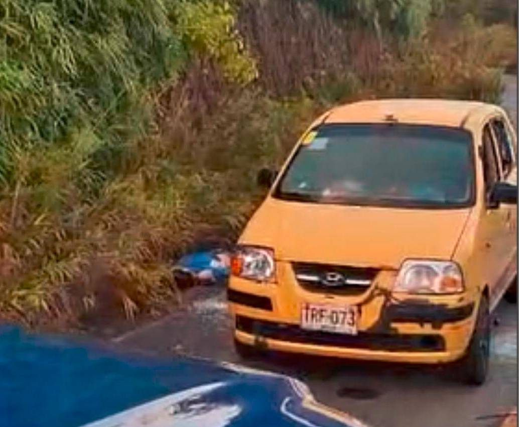 Las dos personas que iban en este taxi fueron acribilladas afuera del automotor, luego de que estructuras armadas lo interceptaran poniendo un árbol en el centro de la vía. IMAGEN TOMADA DE VIDEO.