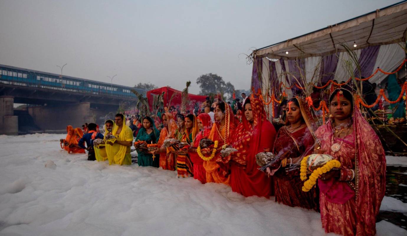 Los devotos hindúes realizan rituales religiosos durante la madrugada mientras esperan la salida del sol para rezar al dios del sol