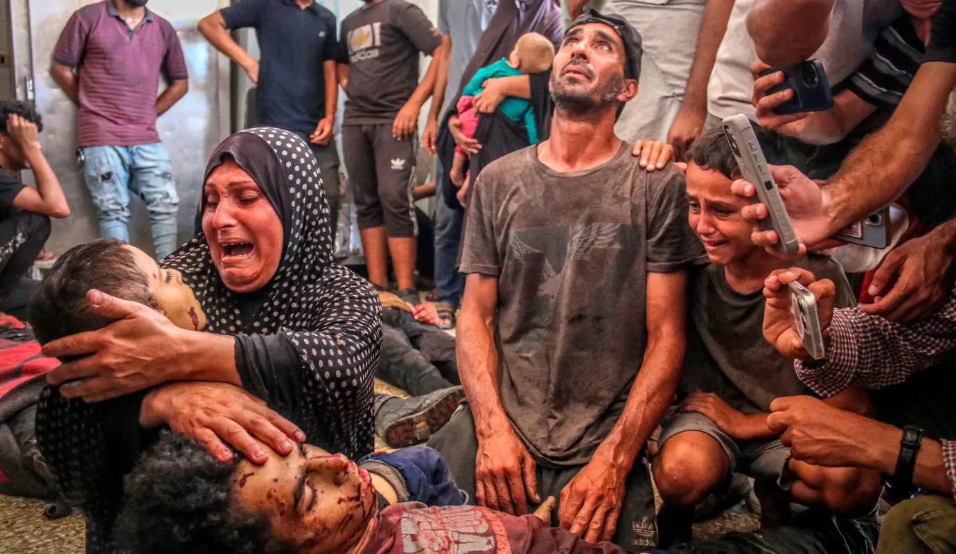 El fotógrafo: Saeed Jaras / Palestine, fue el ganador de la Foto del Año. Una madre y un padre abrazan a sus hijos que murieron en un ataque aéreo israelí contra su tienda de campaña en la ciudad de Deir al-Balah, en el centro de la Franja de Gaza, el 28 de agosto de 2024. 