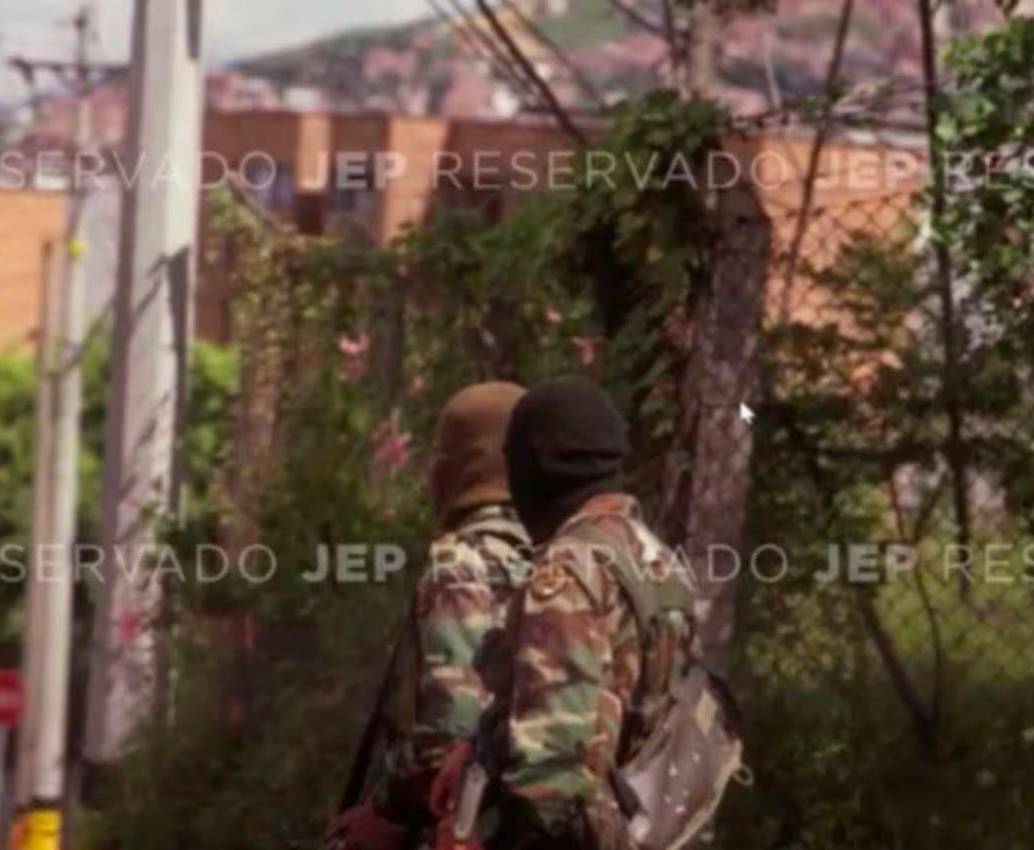 La foto que expuso la JEP durante la audiencia, muestra a dos hombres con camuflado militar, capuchas y fusiles terciados. FOTO: CORTESÍA JEP.