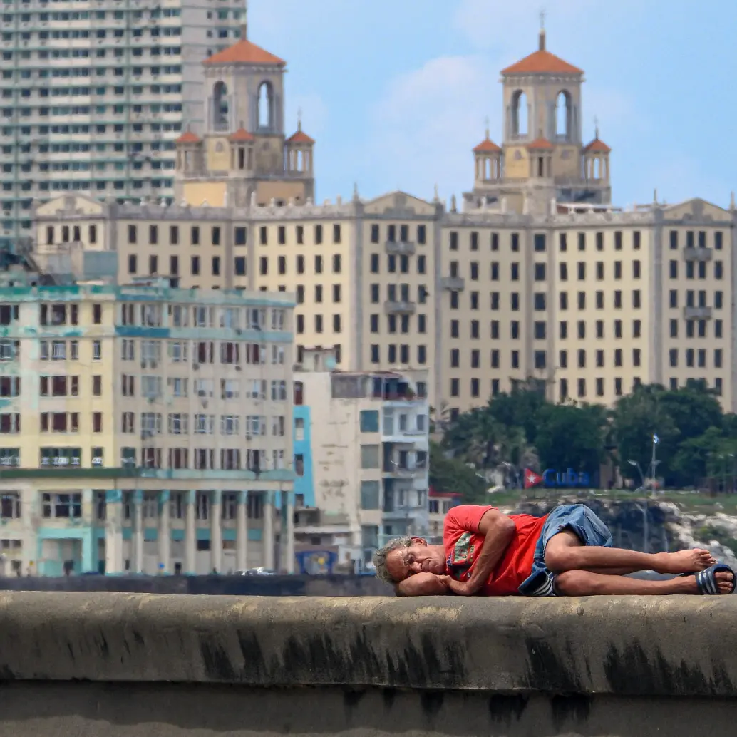 Un hombre duerme en el Malecón de La Habana. Los niveles de pobreza han aumentado drásticamente mientras Cuba enfrenta su peor crisis económica en tres décadas, caracterizada por una grave escasez de alimentos, medicinas y combustible, además de apagones diarios. Foto: AFP