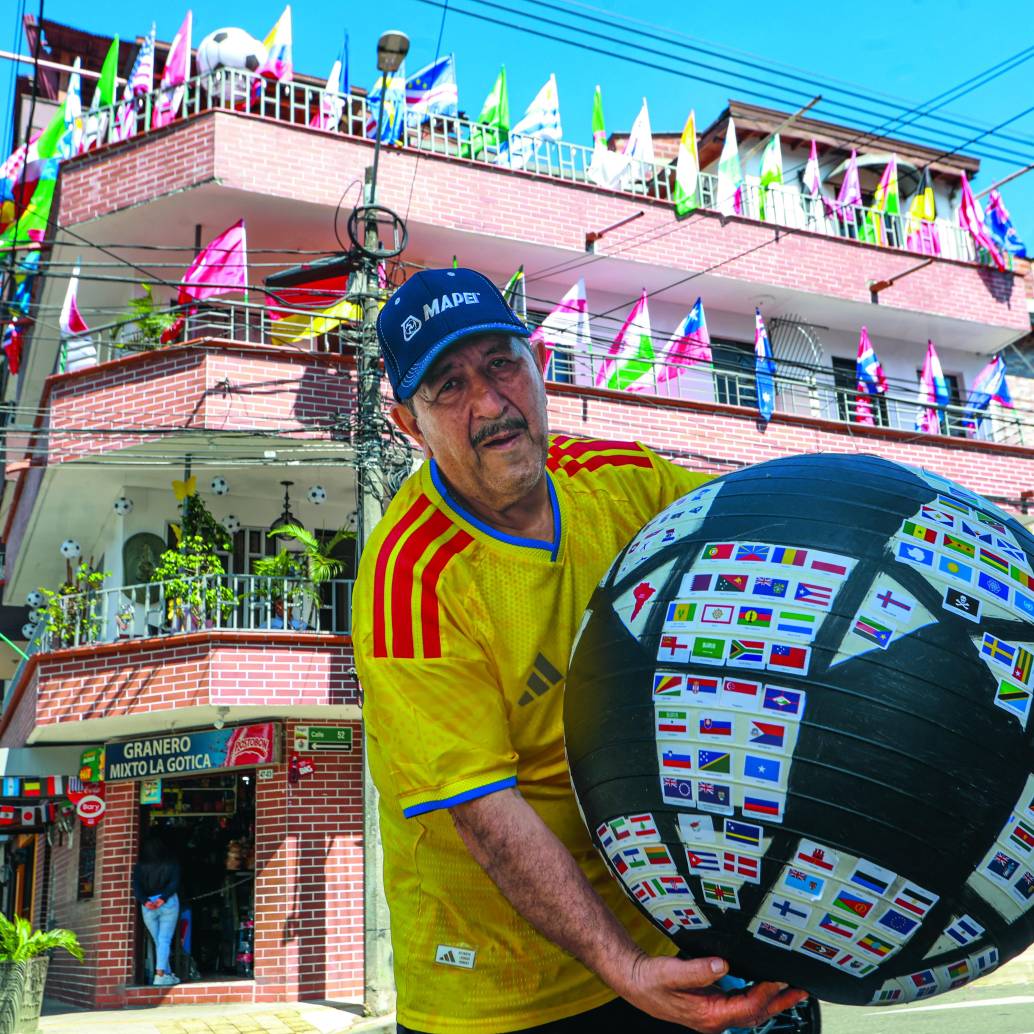 Don Gustavo posando con el ‘balón mundialista’, decorado con más de 300 banderas de las selecciones que han participado a lo largo de la historia en las copas mundiales de fútbol. FOTO Manuel Saldarriaga. 