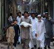 Un hombre carga el cuerpo de un recién nacido que murió tras el incendio en Pakistán. Foto: AFP.