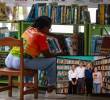 Adelante, los directivos de las entidades que hicieron posible la entrega de las bibliotecas. Atrás ,imagen de referencia de una biblioteca pública. FOTO: Cortesía y Manuel Saldarriaga.