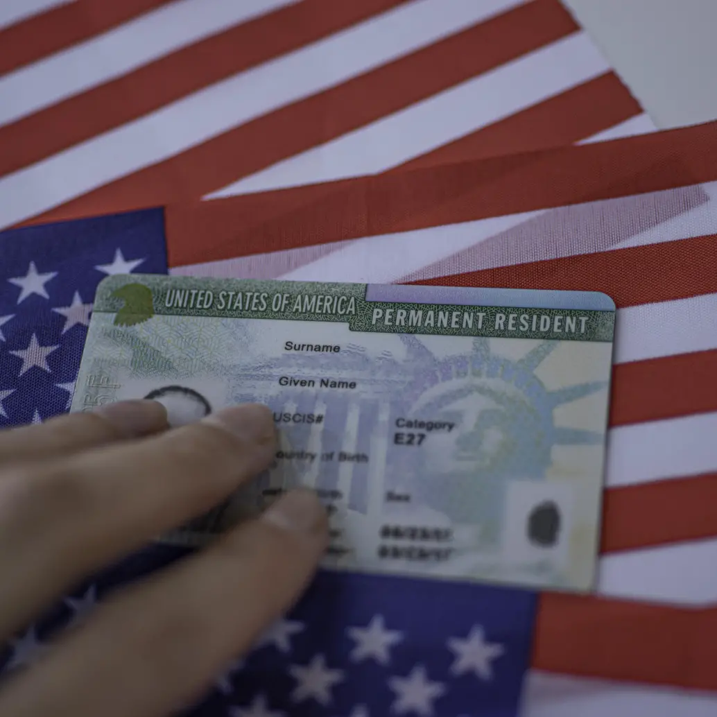 Permanent Resident Green card of United states of America on flag of USA. Above close up view.