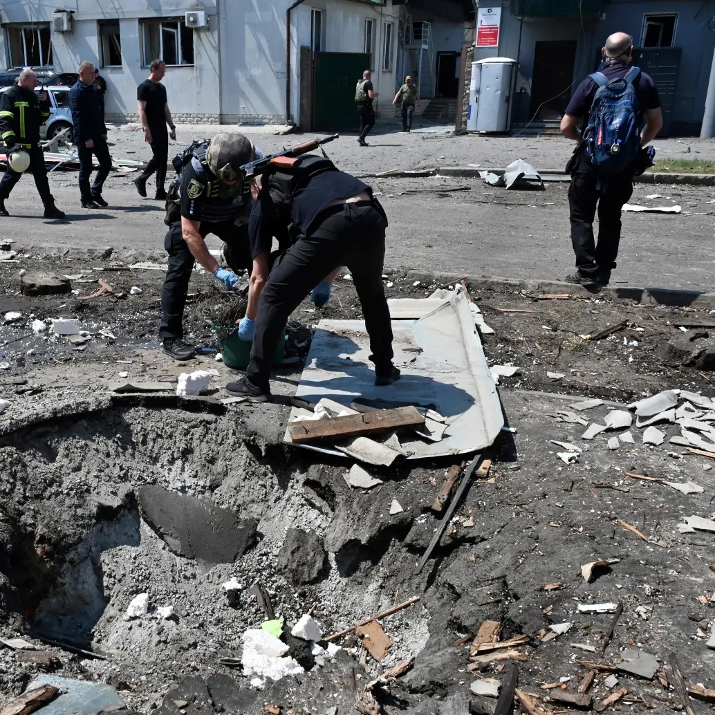 Agentes policiales ucranianos trabajan junto a un cráter tras un ataque con aviones no tripulados. FOTO: AFP