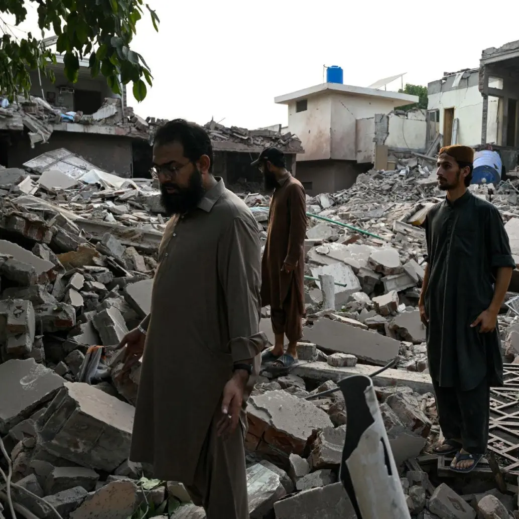 Residentes locales permanecen sobre los escombros de las estructuras destruidas en Pakistán. Foto: AFP