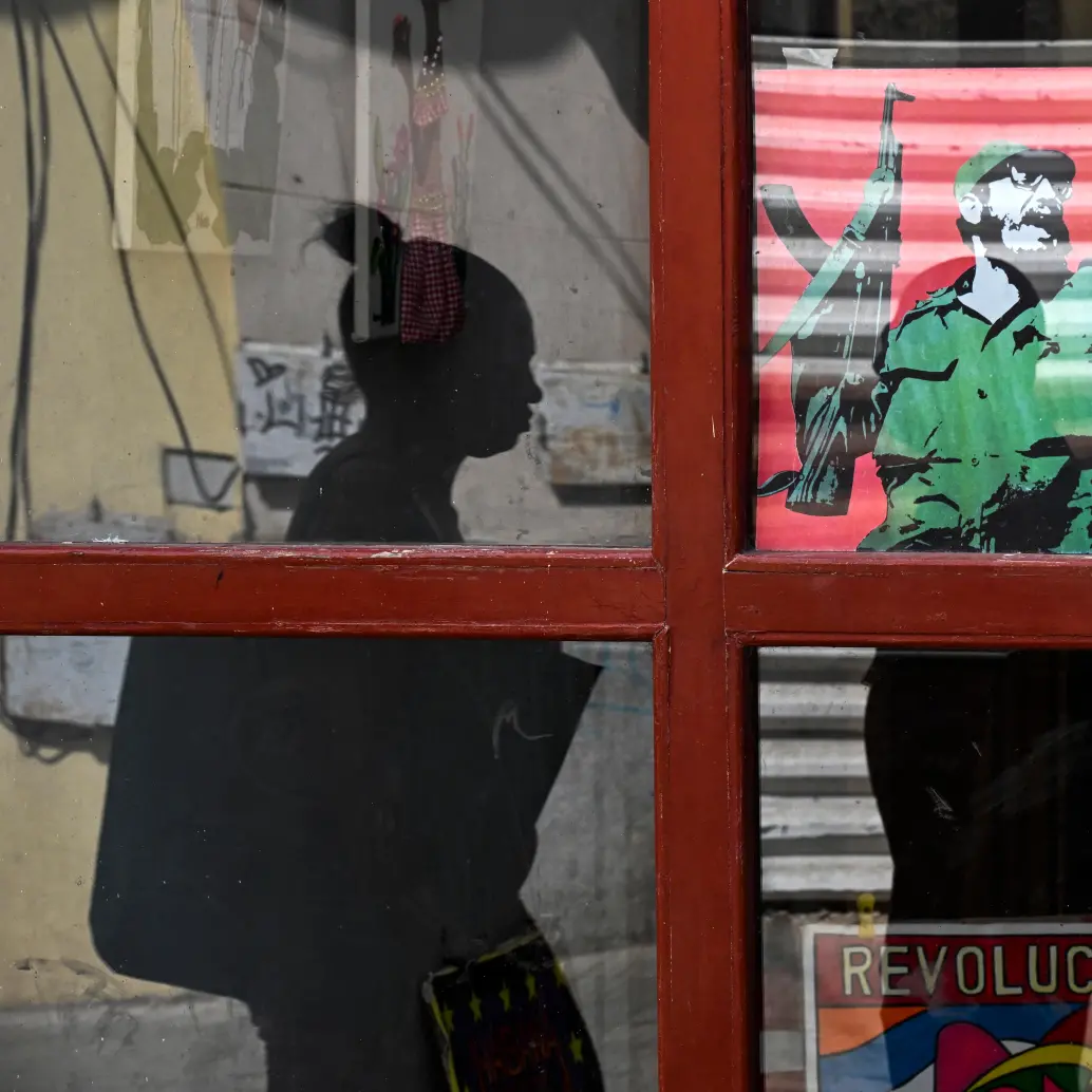 Una mujer pasa junto a un cartel del difunto líder cubano Fidel Castro. Foto Afp