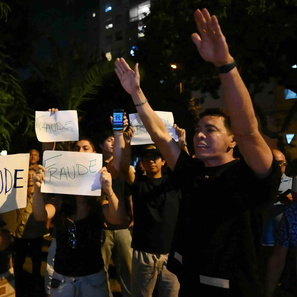 Manifestantes muestran carteles que dicen “Fraude” mientras participan en una protesta tras los primeros resultados de la elección presidencial frente a la sede del Jurado Nacional de Elecciones (JNE) en Lima. Foto: AFP
