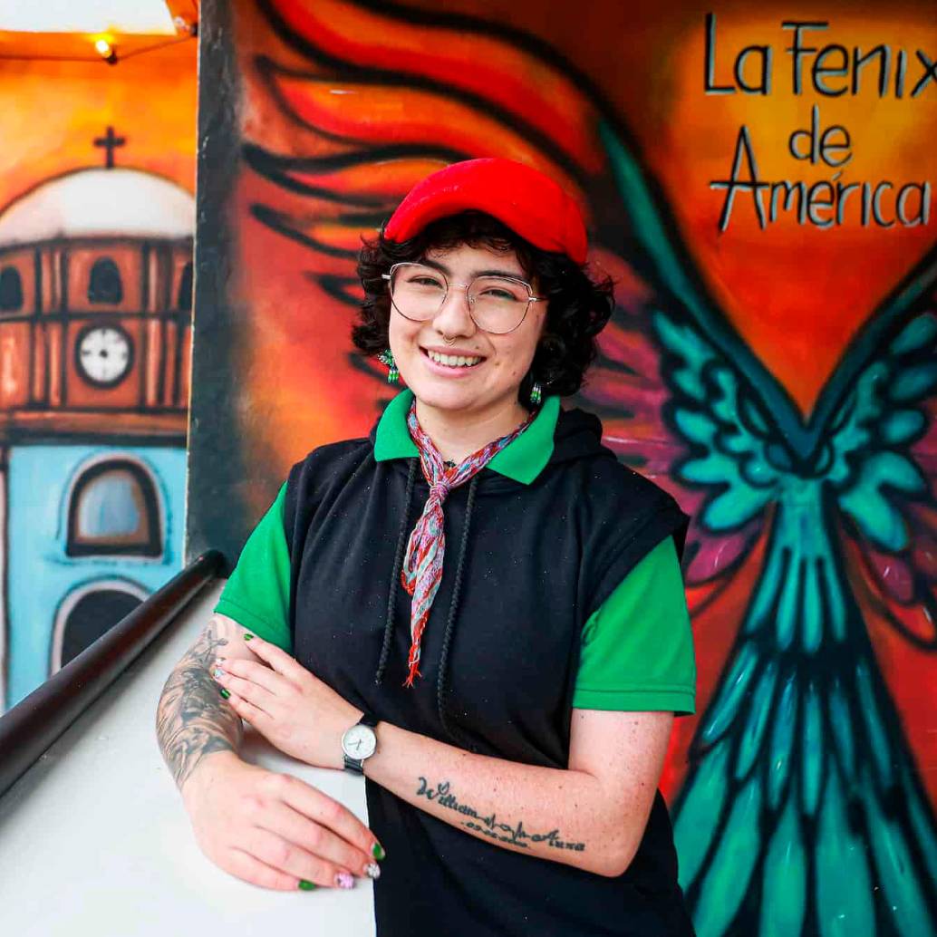 Daniela posa frente a uno de los murales que ha hecho en El Peñol. Su trabajo hace énfasis en la historia del municipio. FOTO Manuel Saldarriaga