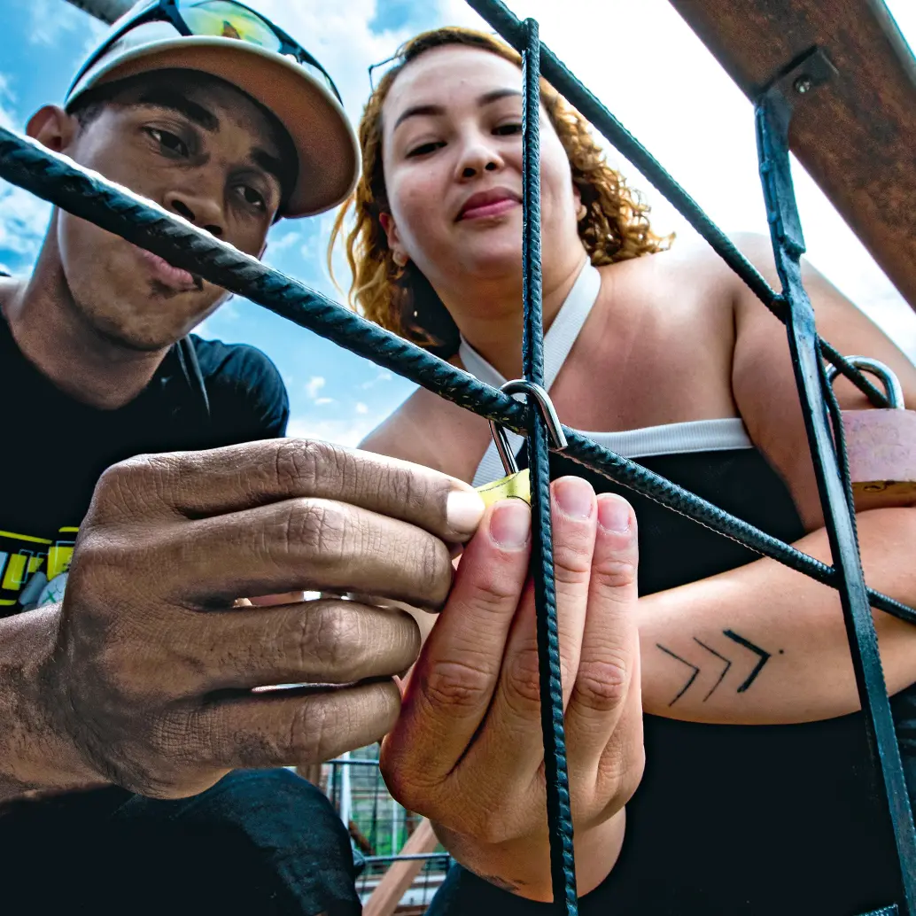 David Mesa y Jeimy Montoya, en el momento en que realizaban el ritual del candado en el Puente de Occidente. Lo hicieron a hurtadillas, como si temieran ser castigados. FOTO Julio César Herrera