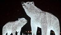 En Moscú un hombre toma una foto de esculturas de osos polares hechas con luz, instaladas para las vacaciones de Año Nuevo y Navidad. FOTO AFP