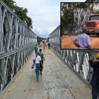 Adelante, un vehículo pesado pasando sobre el puente militar. Atrás, la estructura instalada sobre el río. FOTO: imágenes tomada de redes.