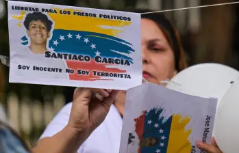Una mujer cuelga fotografías de presos políticos en una cuerda durante una vigilia exigiendo su liberación frente a la Corte Suprema de Justicia en Caracas. FOTO: AFP