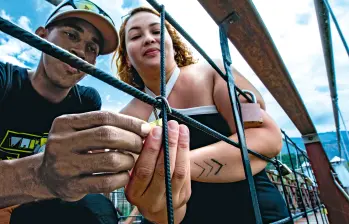 David Mesa y Jeimy Montoya, en el momento en que realizaban el ritual del candado en el Puente de Occidente. Lo hicieron a hurtadillas, como si temieran ser castigados. FOTO Julio César Herrera