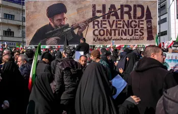 Una pancarta que representa al ayatolá Mojtaba Jamenei, el nuevo Líder Supremo de Irán e hijo del fallecido líder ayatolá Alí Jamenei, es exhibida mientras se le muestra empuñando un arma en la plaza Enghelab (Revolución) en Teherán, el 11 de marzo de 2026, mientras los asistentes se reúnen para los funerales de comandantes del Cuerpo de la Guardia Revolucionaria Islámica (CGRI), el ejército y otros fallecidos en los primeros días de los ataques de Estados Unidos e Israel contra Irán. El Líder Supremo de Irán, el ayatolá Alí Jamenei, murió en los ataques del 28 de febrero, y desde entonces el conflicto ha escalado en ataques de represalia por toda la región. (Foto de Khoshiran / Middle East Images vía AFP)