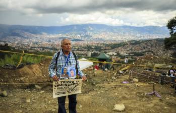 Uno de los familiares de una de las víctimas de La Escombrera muestra las fotos de sus seres queridos junto a un cartel. Foto: Andrés Camilo Suárez Echeverry