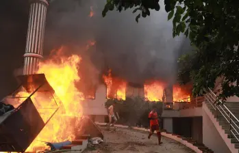 Manifestantes corren junto a las llamas frente a la sede del Partido del Congreso Nepalí incendiada en Katmandú, durante las protestas del 9 de septiembre de 2025 contra la corrupción y la represión policial. FOTO: AFP