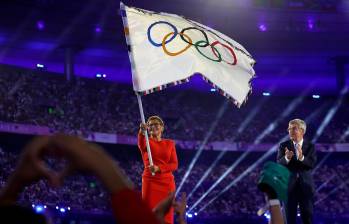 Karen Bass, alcaldesa de Los Ángeles, ondea la bandera olímpica mientras Thomas Bach, presidente del Comité Olímpico Internacional, aplaude durante la ceremonia de clausura de los Juegos. FOTO: GETTY