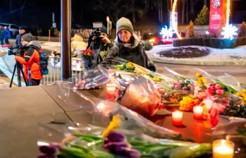Una mujer pone flores cerca del lugar donde un incendio arrasó un bar abarrotado durante las celebraciones de Nochevieja en la ciudad de Crans-Montana. FOTO: AFP