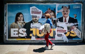 Una mujer camina frente a una propaganda de la coalición política Juntos Por el Cambio en Buenos Aires.