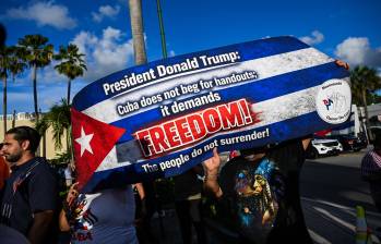 Varias personas sostienen un cartel frente al restaurante Versailles en Miami, Florida, en apoyo a los cargos presentados por la fiscalía federal estadounidense contra el expresidente cubano Raúl Castro. Se han avivado las especulaciones sobre un posible intento del presidente Donald Trump de derrocar al régimen comunista. Foto: AFP