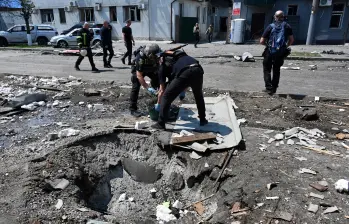 Agentes policiales ucranianos trabajan junto a un cráter tras un ataque con aviones no tripulados. FOTO: AFP