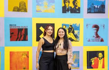 Paulina Castro y Mónica Torres junto al mural Escuchando el tiempo: 40 años, 40 discos, ganador de la Convocatoria Nuevos Talentos en el Arte de la Cámara de Comercio de Medellín para Antioquia. FOTO: Cámara de Comercio de Medellín