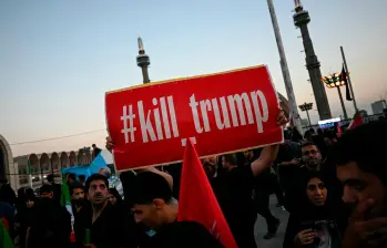 Un hombre sostiene una pancarta que pide venganza contra el presidente de Estados Unidos mientras los dolientes se reúnen para rendir homenaje al líder supremo de Irán, el ayatolá Ali Jamenei. FOTO: AFP