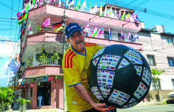Don Gustavo posando con el ‘balón mundialista’, decorado con más de 300 banderas de las selecciones que han participado a lo largo de la historia en las copas mundiales de fútbol. FOTO Manuel Saldarriaga. 