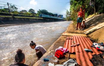 La rutina de la familia varada en Medellín incluye baños en el río, donde también lavan la ropa. Armaron las carpas bajo un árbol para resguardarse de la lluvia. FOTO ESNEYDER GUTIÉRREZ CARDONA