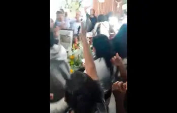 Momento en el que los asistentes al velorio auxiliaban al hombre que velaban cuando empezó a golpear el ataúd. FOTO: Captura de video