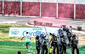 Este es uno de los cobros de tiro de esquina en los que Edwin Cardona es cuidado por un grupo de policías para protegerlo de los objetos que le lanzaban desde las tribua. FOTO CORTESÍA NACIONAL 
