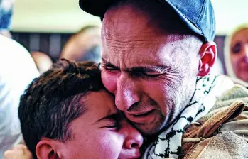 Un preso palestino, liberado tras intercambio de presos y rehenes y el acuerdo de alto el fuego entre Israel y Hamás, abraza a un niño a su llegada en autobús a Ramalla. FOTO AFP