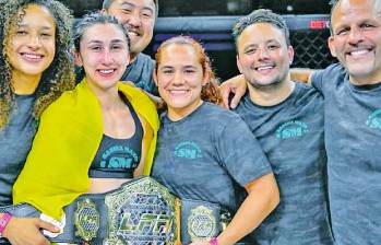 La antioqueña Sabina Mazo con su equipo de trabajo y el cinturón que la acredita como la campeona mundial. FOTO CORTESÍA