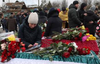 Momentos del funeral de la familia Kravchenko y su hija, sobreviviente, llorando encima del féretro. FOTO: AFP