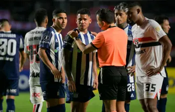 Miguel Navarro, de Talleres, junto al árbitro chileno Piero Maza. FOTO: AFP