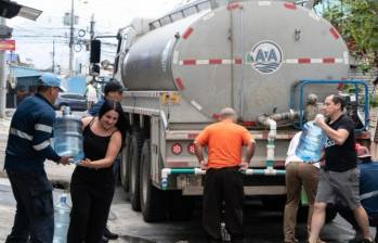 Personal del Instituto Costarricense de Acueductos y Alcantarillados de Costa Rica, va de barrio en barrio entregando agua potable a las familias más afectadas de la capital. FOTO: AFP