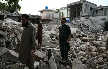 Residentes locales permanecen sobre los escombros de las estructuras destruidas en Pakistán. Foto: AFP