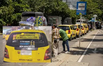 Adelante, uno de los taxis con su respectivo mensaje. Atrás, un acopio de taxis en Bello. Foto: EL COLOMBIANO