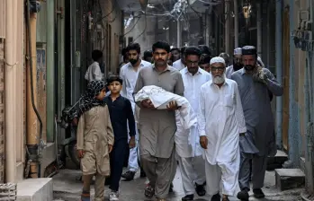 Un hombre carga el cuerpo de un recién nacido que murió tras el incendio en Pakistán. Foto: AFP.