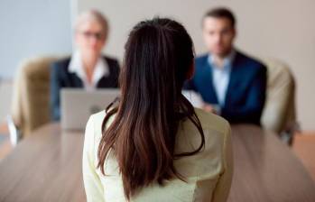 Mujer realizando una entrevista de trabajo en una mesa frente a dos reclutadores. FOTO: Shutterstock